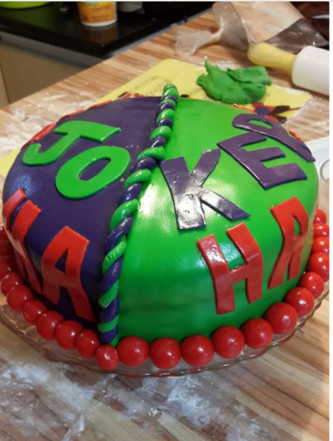 Bolo redondo em verde e roxo com escrito "Joker"