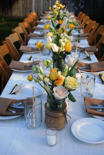 Mesa de convidados rústica decorado com vasos com flores amarelas e laranjas