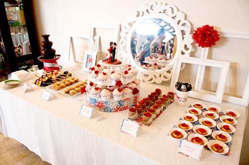 Mesa com decoração branca e detalhes de vermelho apenas nos doces e flores