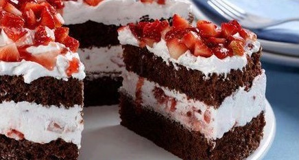 Pedaço de bolo floresta negra com morango em cima e no recheio.