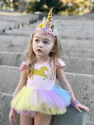Menina vestida com camiseta de unicórnio, saia tutu e tiara.