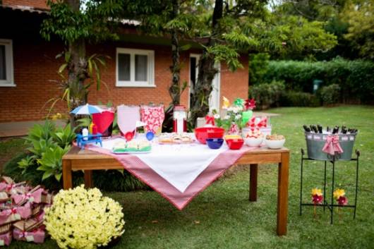 mesa de madeira com toalha de xadrez vermelha e branca em festa piquenique