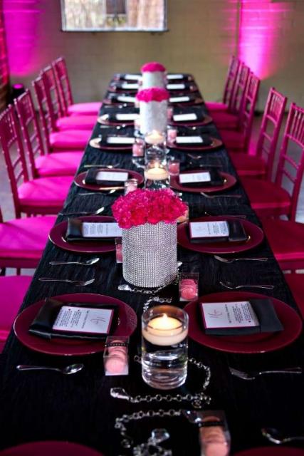 Mesa preta e cadeiras rosas.