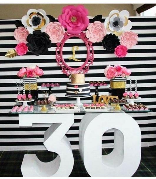 Festa de 30 anos com mesa de vidro e flores decorativas.