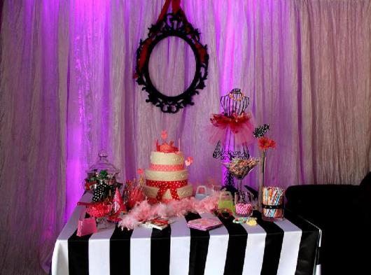 Mesa decorada com detalhes cor de rosa e toalha em preto e branco.