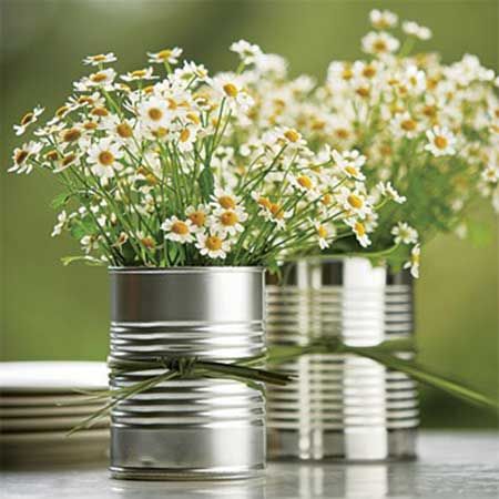 Latas servindo como vasos de flores brancas.