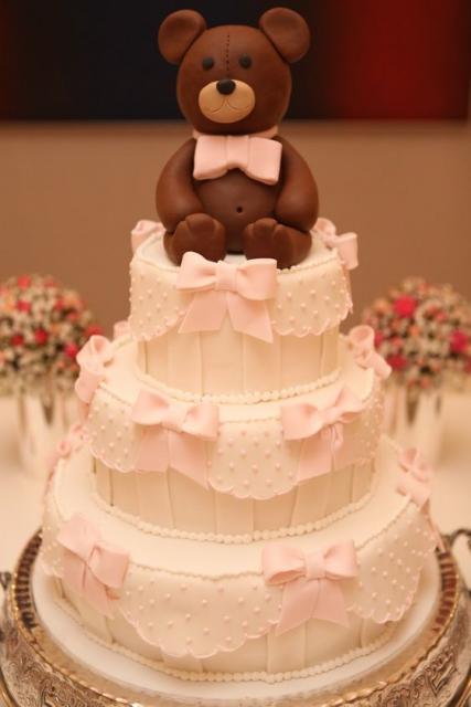 Bolo de batizado feminino com ursinho de biscuit e lacinhos decorando