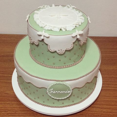 bolo de batizado azul com detalhes brancos e dourados, e pombinhas brancas