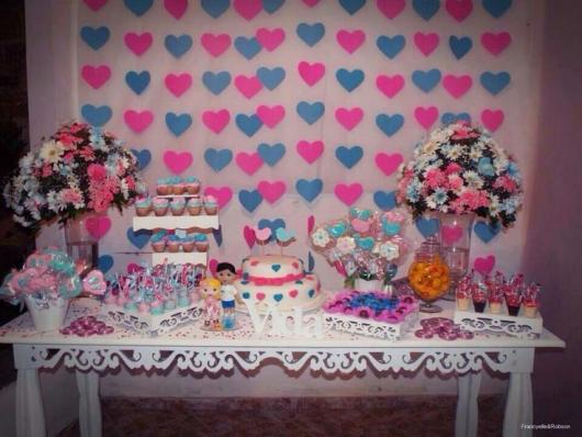cortina de corações azul e rosa ao fundo da mesa de doces