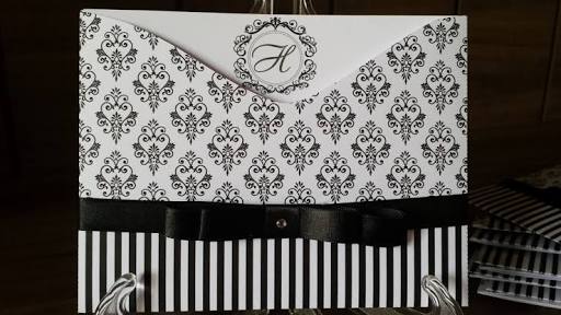 convite branco com detalhes em preto, inclusive laço