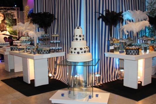 mesas de doces com plumas encima e bolo de flores ao meio