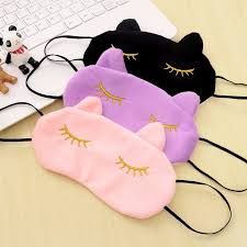 Três máscaras de dormir, uma rosa, uma lilás e uma preta.