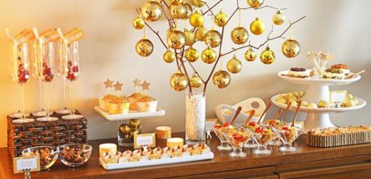 Mesa de comidas decorada com bolas douradas.