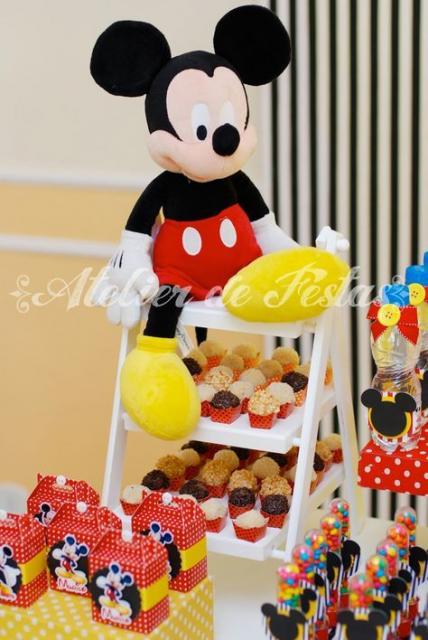 Mini escada em cima de mesa, com docinhos e Mickey de pelúcia.
