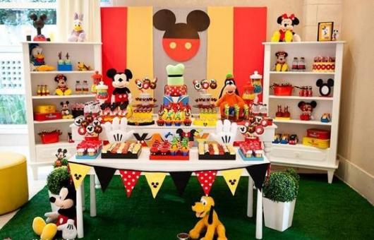 Mesa de bolo em cima de tapete de grama e decoração com móveis brancos.