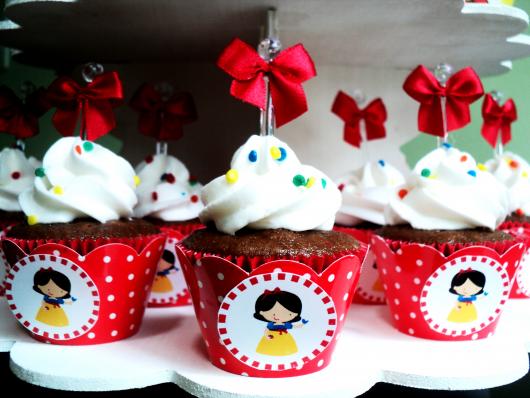 Cupcake Branca de Neve decorado com chantilly branco e lacinho vermelho