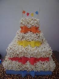 Bolo fake de pipoca com laço de fita azul, vermelho e amarelo