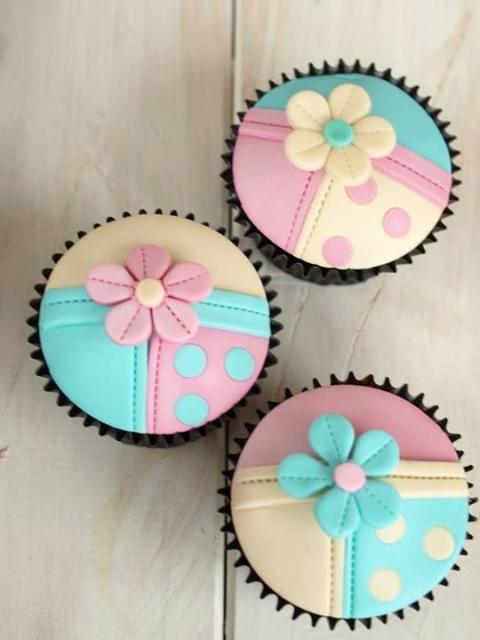 Cupcakes decorados com as cores amarelo, rosa e azul.