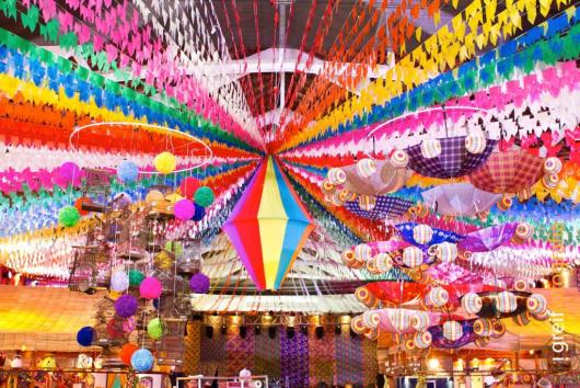 Decoração de Festa Junina Infantil com teto coberto por bandeirinhas coloridas