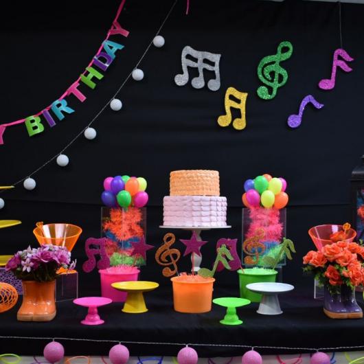 Festa criativa neon com notas musicais decorando a parede