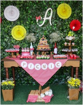 Festa com mesa de madeira e painel de folhas verdes.