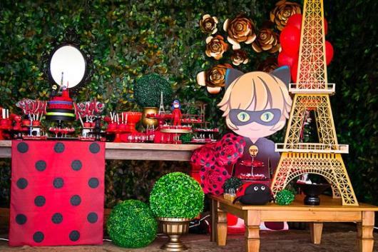 Festa Ladybug, com mesa de madeira e painel de folhas.