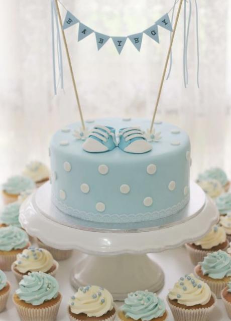 Bolo azul e branco com sapatinho no topo para chá de bebê