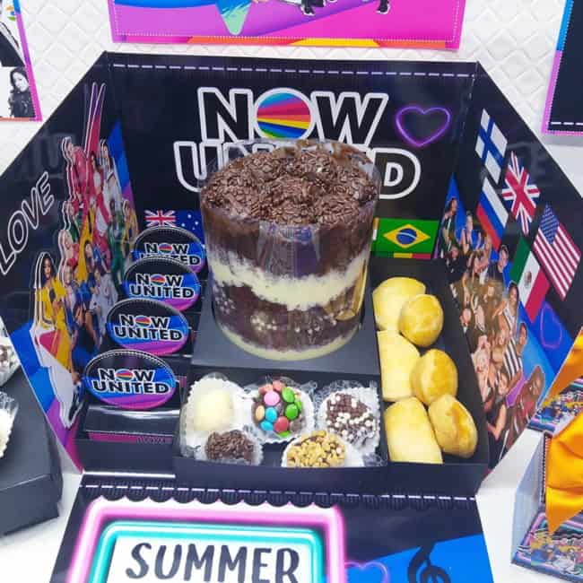 festa Now United na caixa com bolo e docinhos