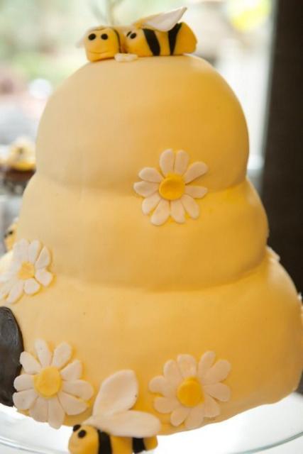 Bolo de três andares na cor amarela com decoração de flores uma abelha no topo