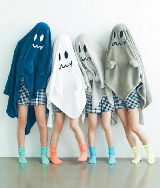 Pessoas com cobertores na cabeça, com fantasmas desenhados no tecido.