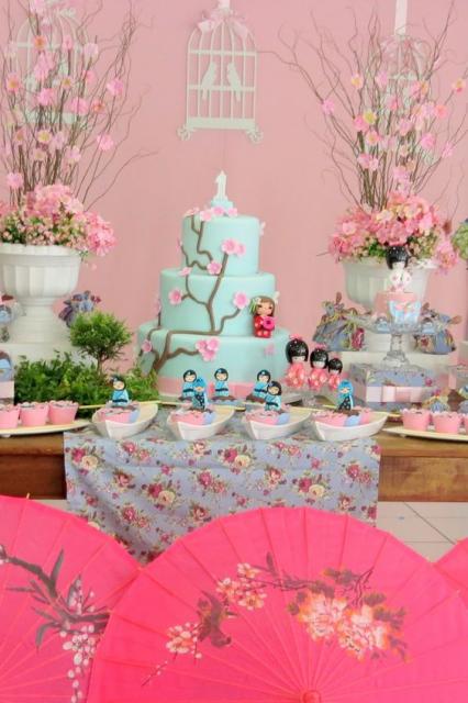mesa decorada de festa japonesa em azul e rosa com sombrinhas na frente