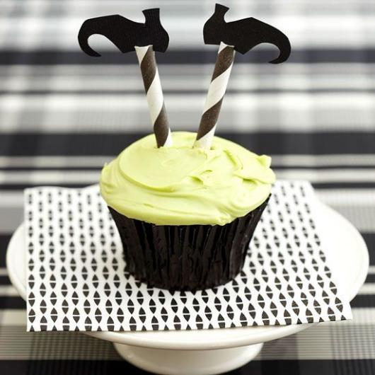 Cupcake com dois palitos com sapatinhos, imitando as pernas de uma bruxa.