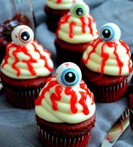Cupcakes com olhos e calda de morango em cima.
