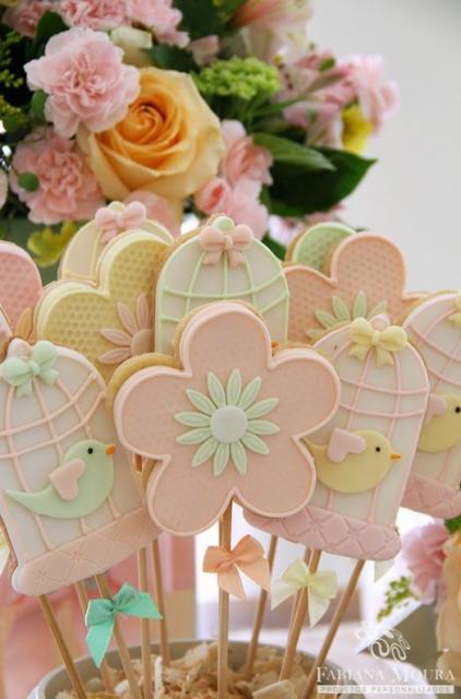 Pirulitos com decoração de flores e gaiolas com passarinhos.