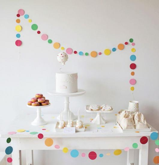 mesa de bolo e doces branco com enfeito colorido ao redor para festa de 18 anos simples e barata