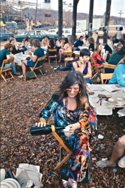 Janis Joplin em festival, com vestido e óculos coloridos.