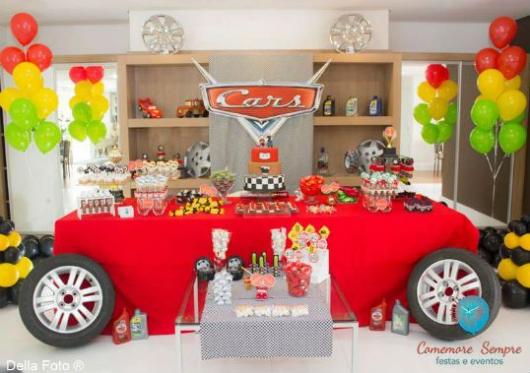 Decoração de festa carros com pneus e toalha de mesa vermelha.