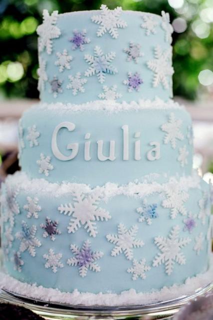 Bolo cenográfico azul com flocos de neve brancos.
