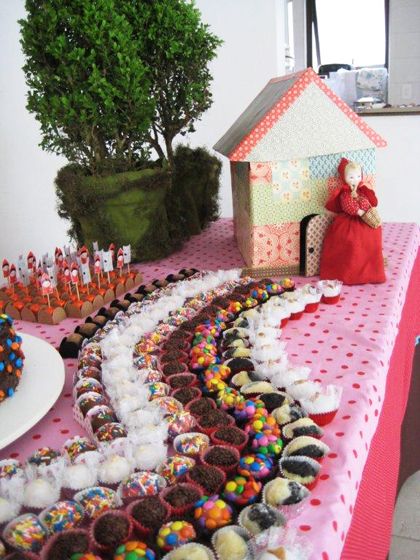 Decoração de mesa de docinhos com o caminho até a casa da avó feito com diferentes doces.