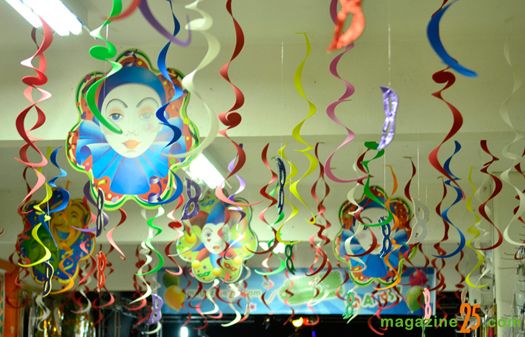 Salão de festa com serpentinas coloridas e máscaras.