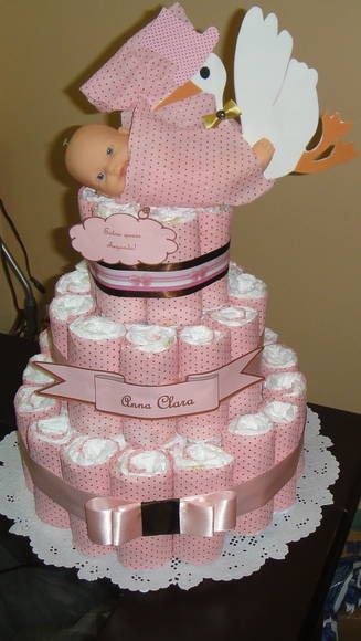 bolo fake feminino com estampa rosa de bolinhas, laço da mesma cor e uma boneca com uma cegonha encima