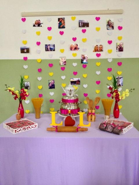 cortina de corações rosa e amarelo ao fundo da mesa de doces