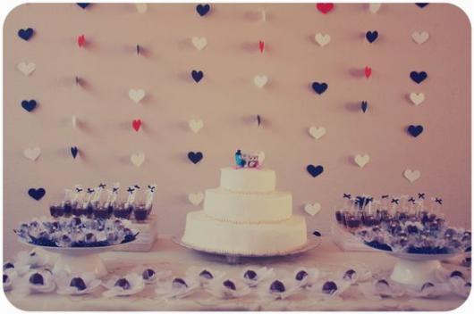 cortina de corações vermelho, preto e branco ao fundo da mesa de doces e bolo com duas corujinhas
