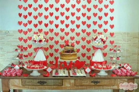 cortina de coração vermelho e branco ao fundo da mesa de doces
