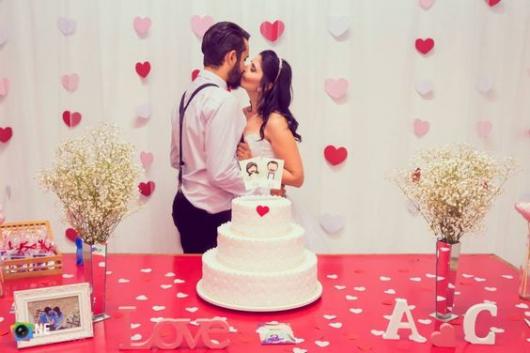 cortina de corações vermelho, rosa e branco com o casal se beijando na frente
