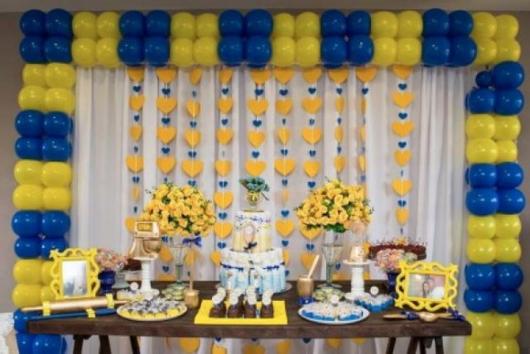 cortina de corações amarelo e azul ao fundo da mesa de doces