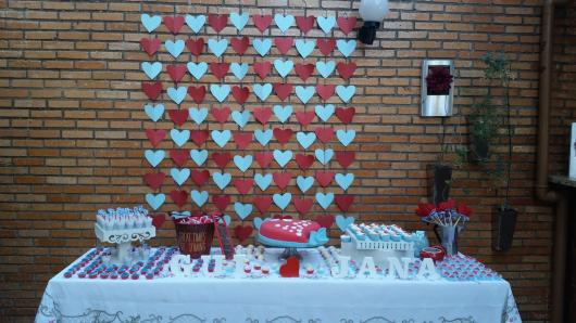 cortina de corações vermelho e azul ao fundo da mesa de doces