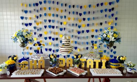 cortina de corações azul e amarelo ao fundo da mesa de doces