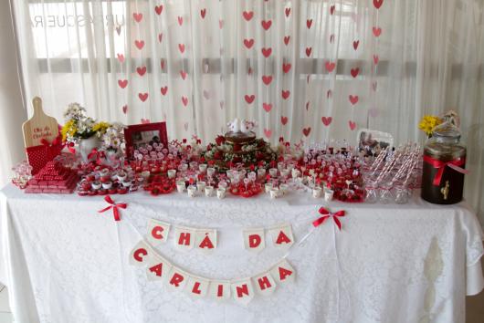 cortina de coração vermelho ao fundo da mesa de doces
