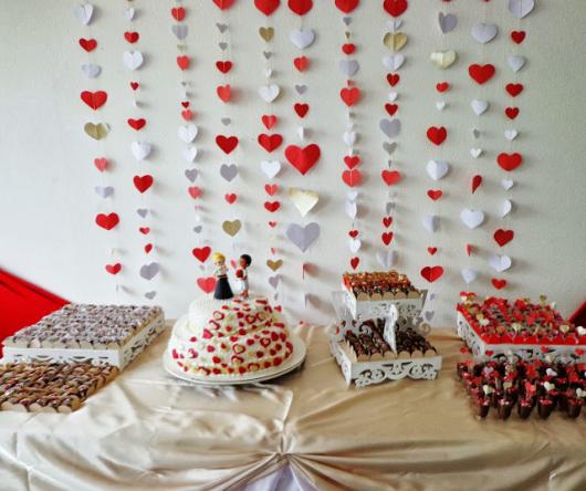 cortina de corações vermelho e branco ao fundo da mesa de doces